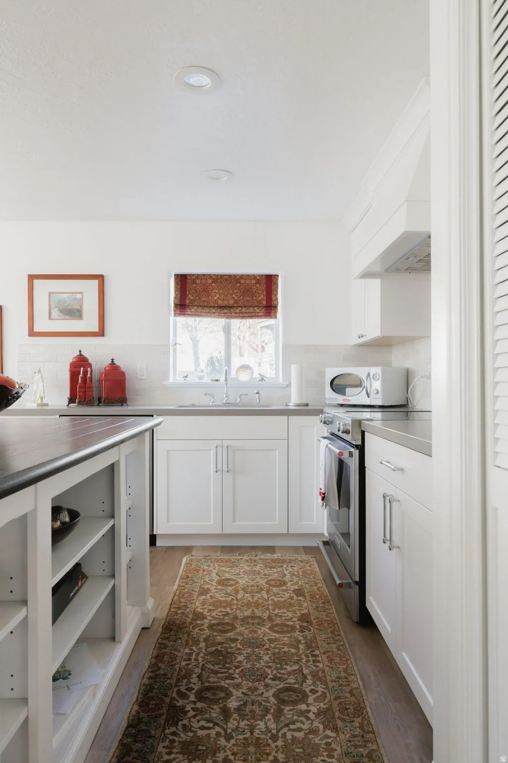 Kitchen with stainless steel range with electric cooktop, white cabinets, light countertops, white microwave, and dark wood finished floors
