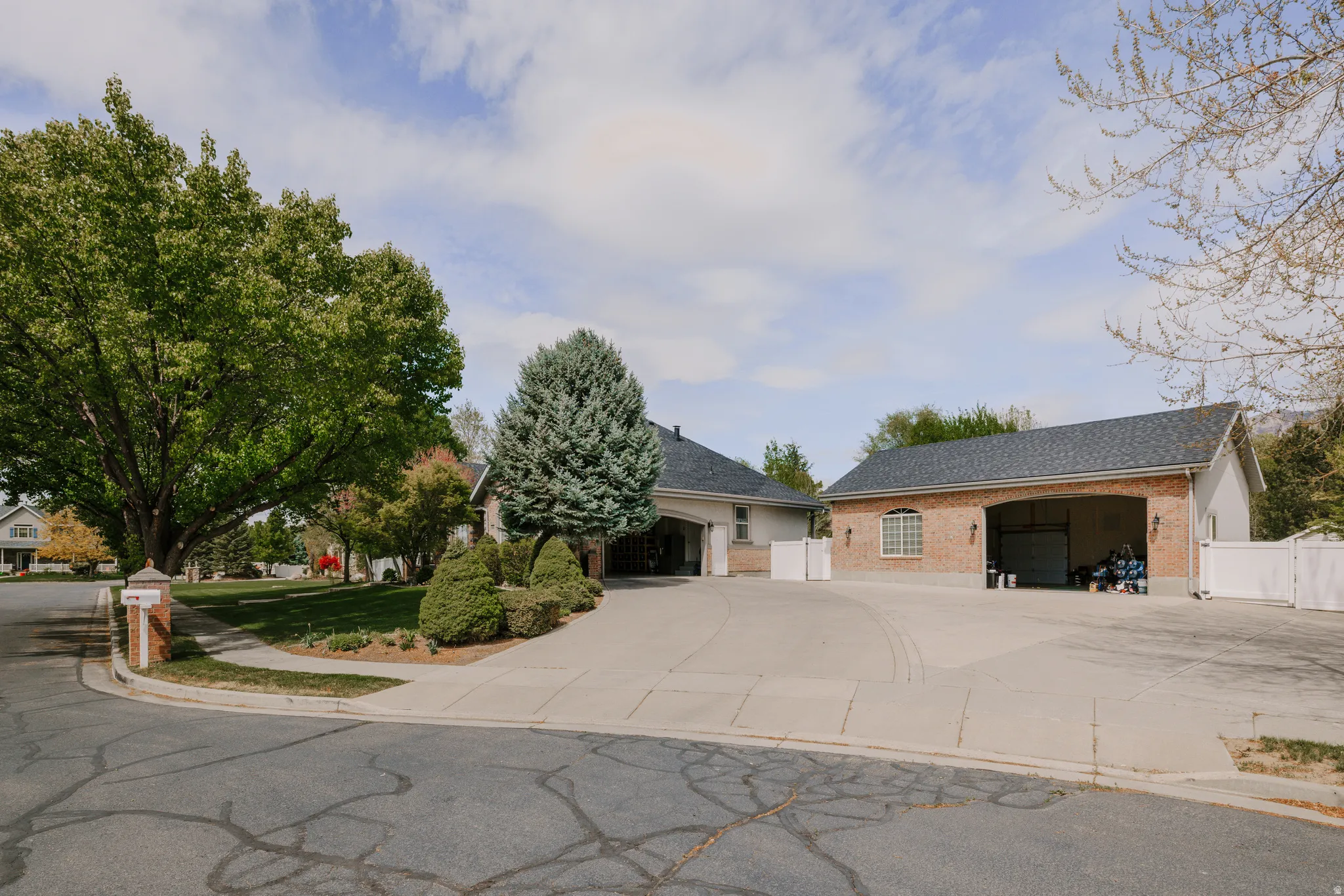 Ranch-style house with brick siding, roof with shingles, a gate, and concrete driveway