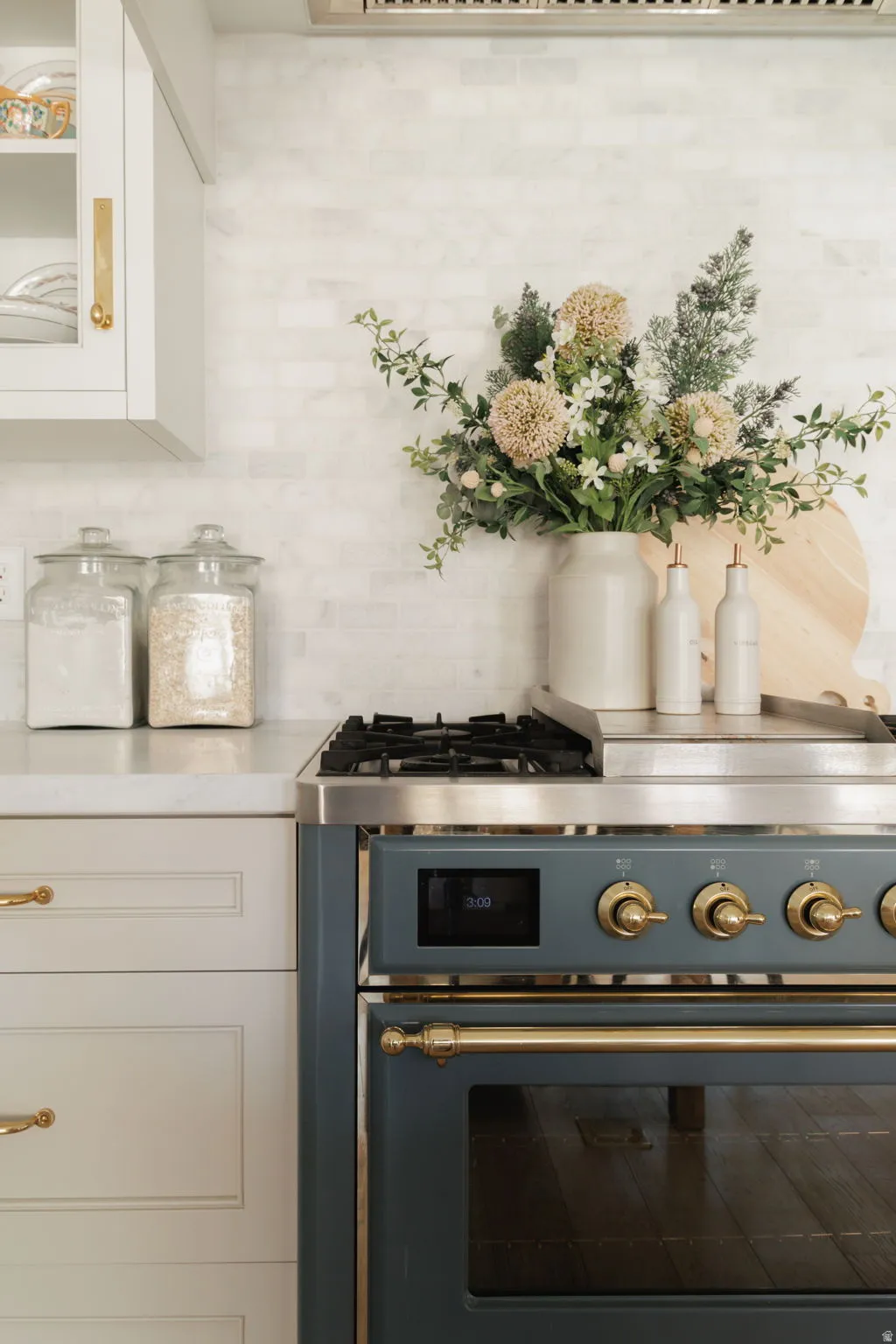 Kitchen view of white cabinets, gas stove, glass insert cabinets, and backsplash