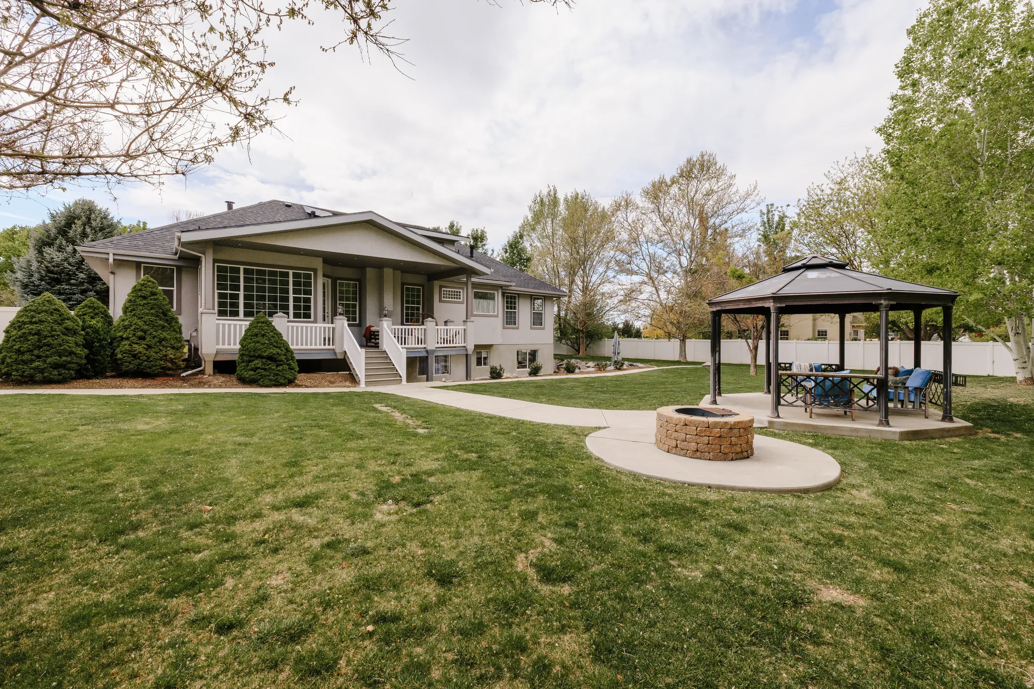 Rear view of property featuring a fenced backyard, an outdoor fire pit, a shingled roof, and a patio