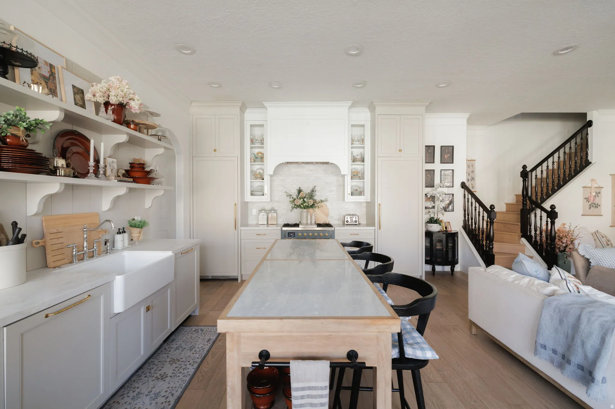Kitchen featuring white cabinetry, open shelves, light wood-type flooring, decorative backsplash, and light stone counters