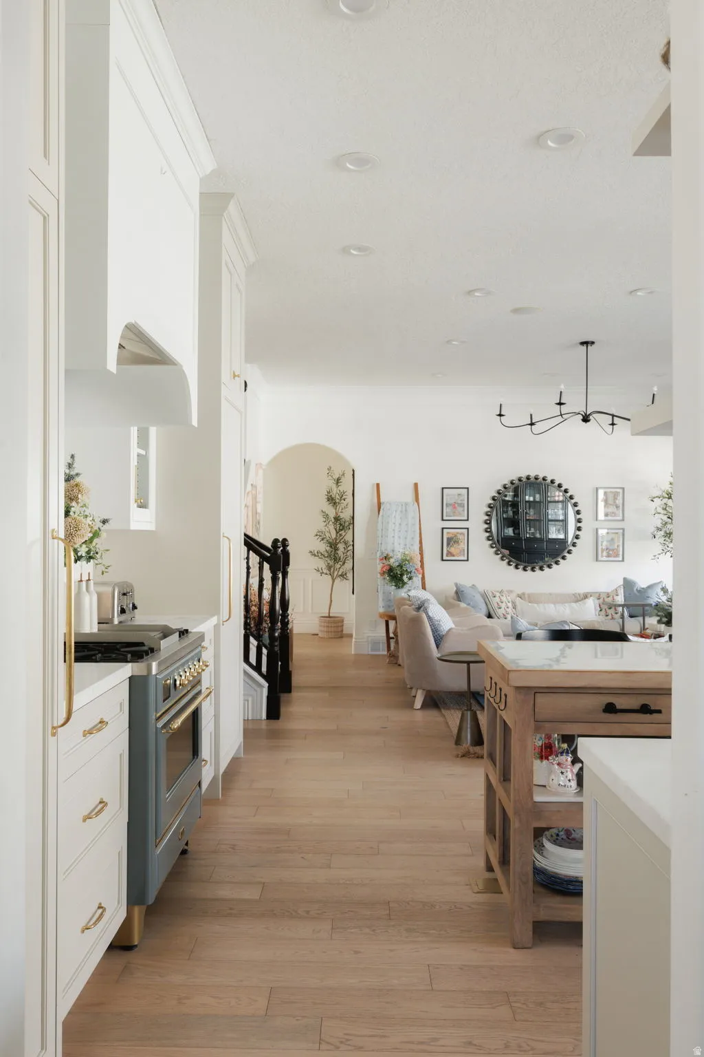 Kitchen featuring arched walkways, white cabinetry, gas stove, light wood-type flooring, and open floor plan