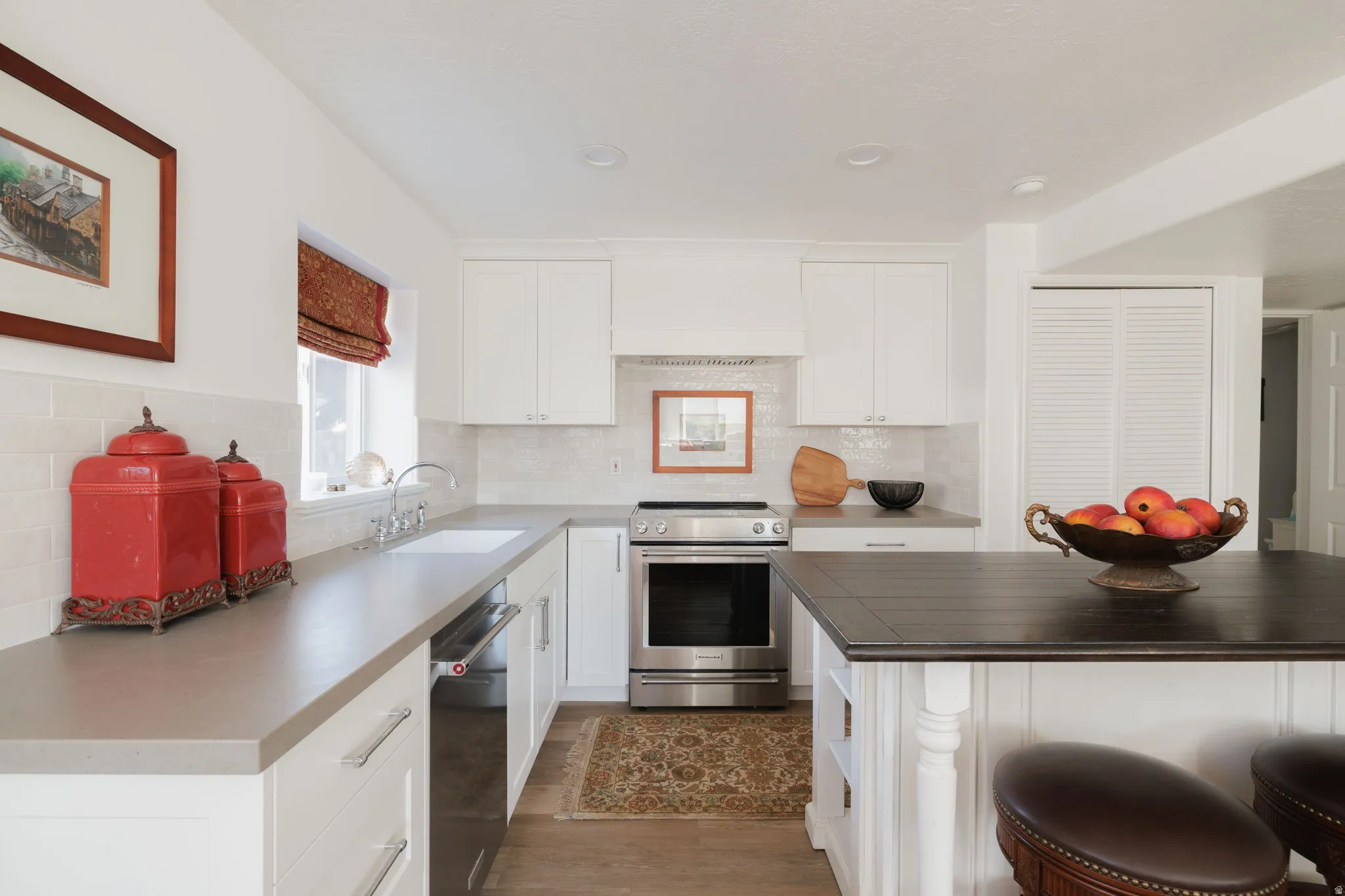 Kitchen with white cabinetry, stainless steel appliances, a kitchen breakfast bar, butcher block counters, and backsplash