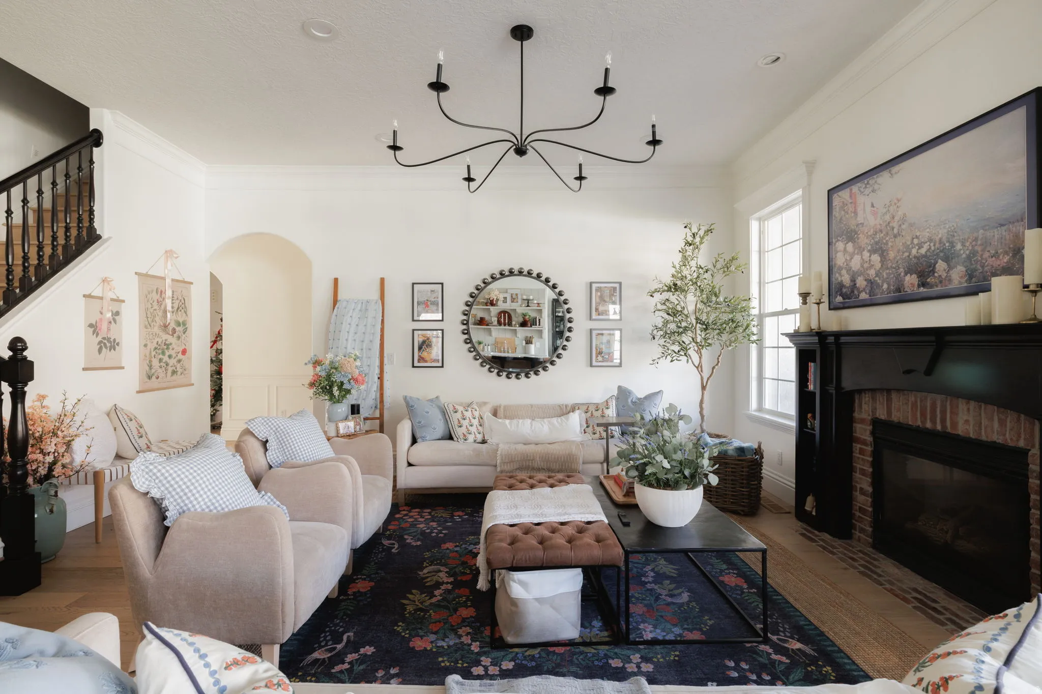 Living area with ornamental molding, a brick fireplace, suspended lighting, wood finished floors, and arched walkways