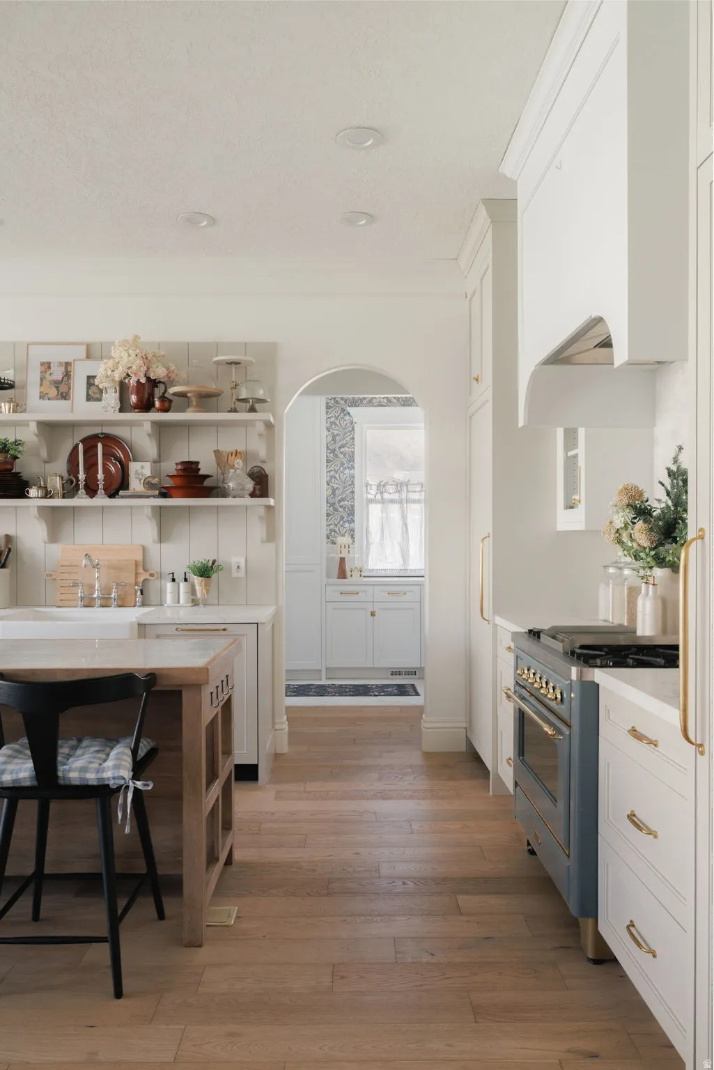 Kitchen with white cabinetry, arched walkways, range with gas stovetop, open shelves, and a textured ceiling