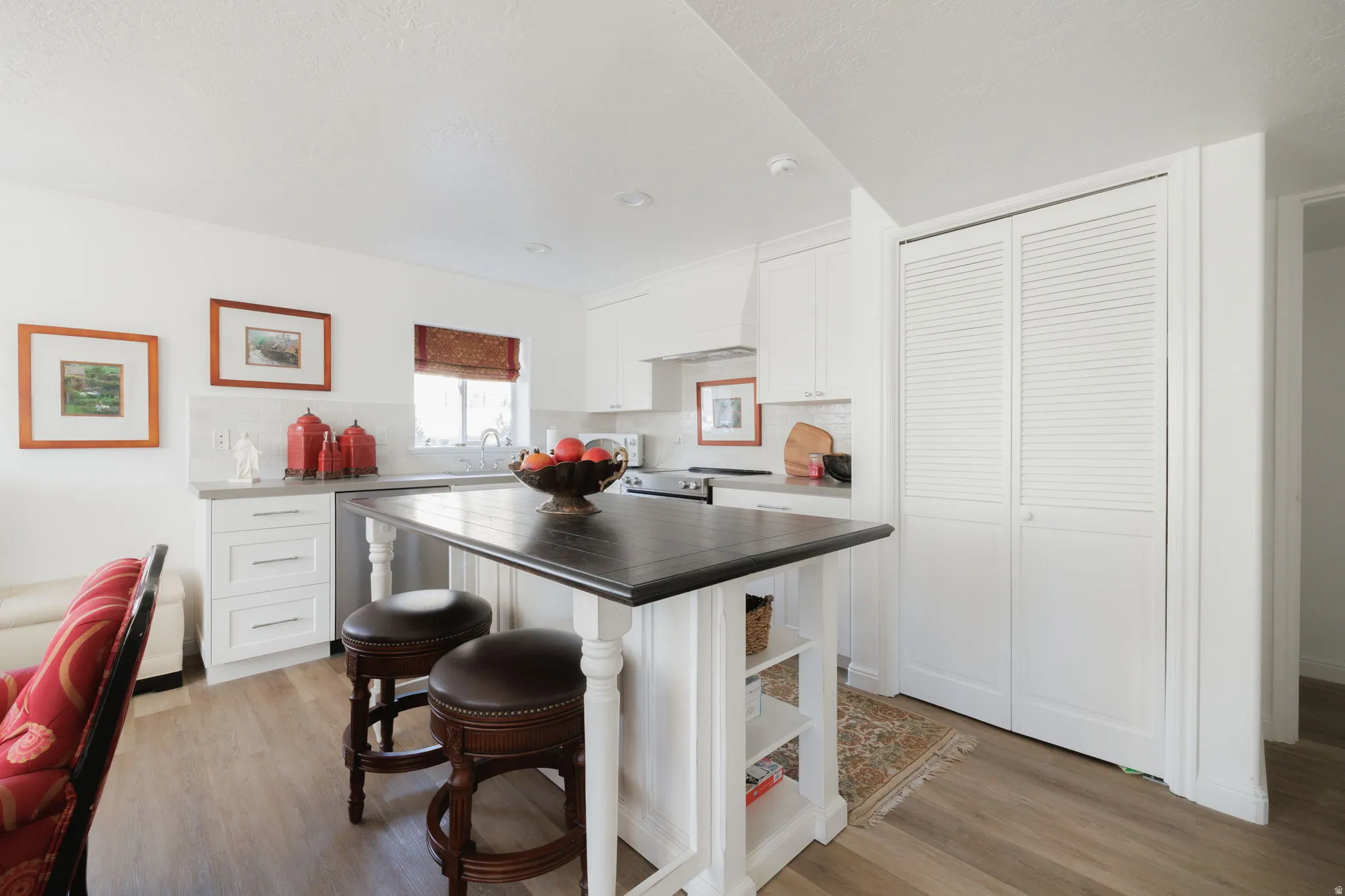 Kitchen with a kitchen breakfast bar, white cabinetry, light wood-style floors, and tasteful backsplash
