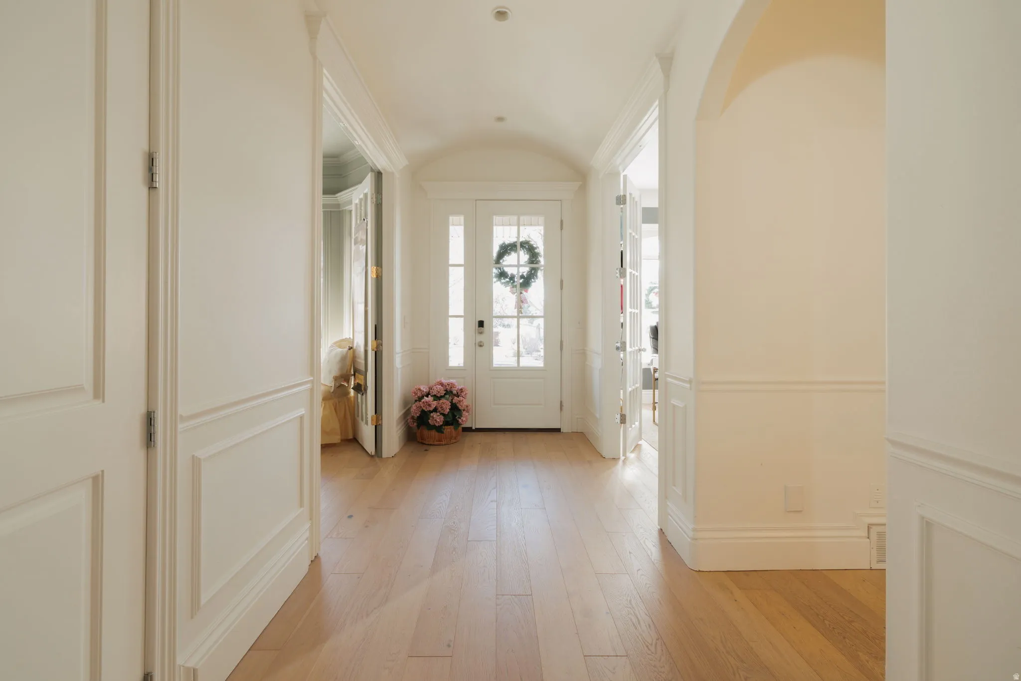 Foyer featuring a barrel ceiling, light wood-style flooring, and arched walkways