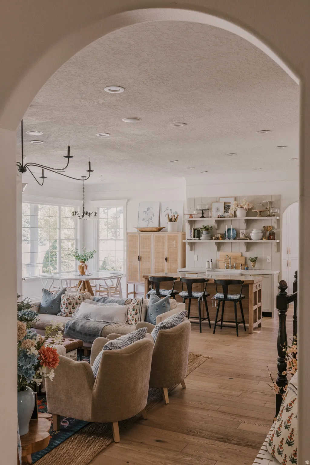 Living area with arched walkways, light wood-style floors, and a textured ceiling