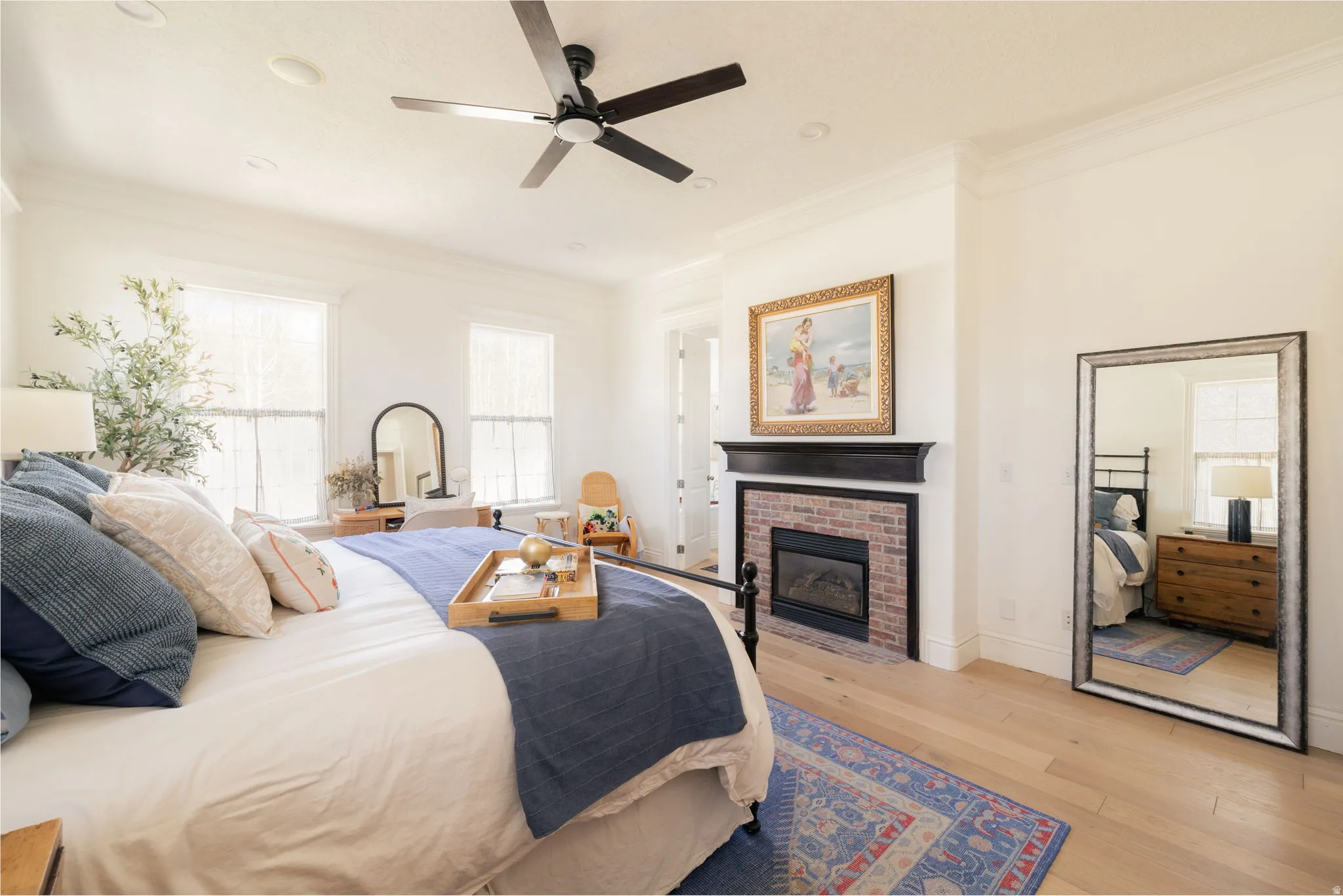 Bedroom with ornamental molding, light wood-type flooring, a fireplace, and a ceiling fan