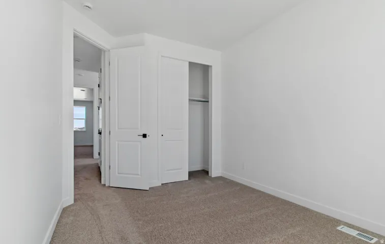 Neutral wall finishes, plush carpet flooring, white trim, and a bi-fold closet door with rod