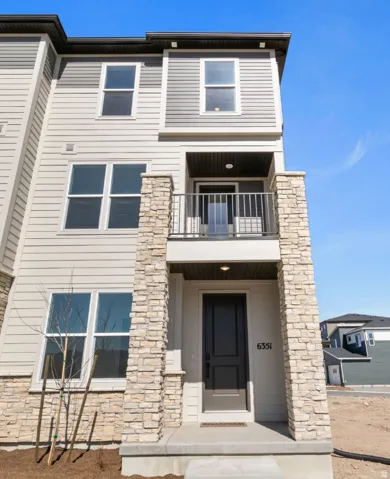 Modern multi-level exterior featuring light siding and stacked stone accents