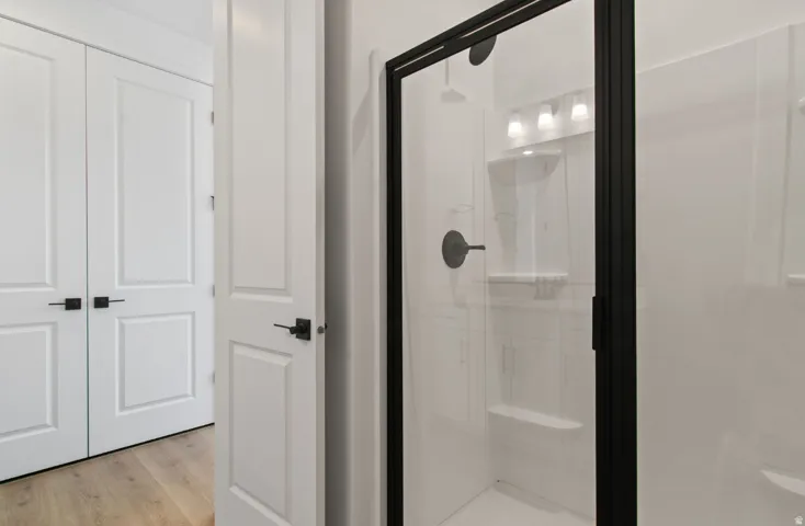 Walk-in shower with a black-framed glass enclosure, integrated shelving, and matte black fixtures
