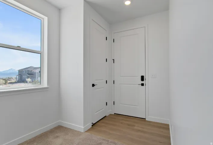 White interior door with contemporary black hardware, recessed ceiling lighting, and light wood-finish flooring