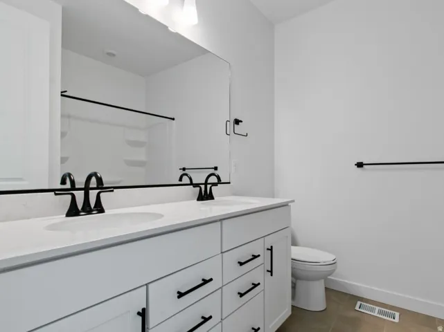 Dual vanity with white cabinetry and dark hardware, featuring white countertops, undermount sinks, and matte black fixtures