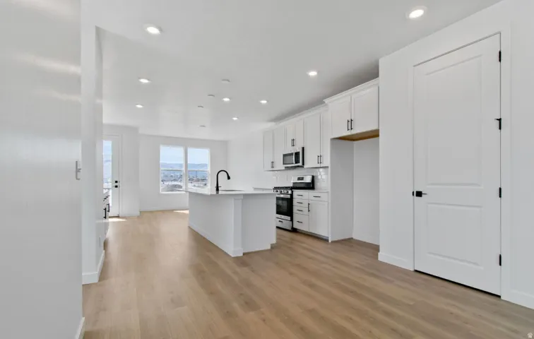 Open-concept living space featuring wood-finish flooring, recessed lighting, and a kitchen with white cabinetry