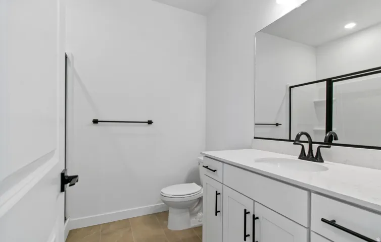 Bathroom featuring a white vanity with an integrated sink, black hardware, black faucet, and a large wall-mounted mirror