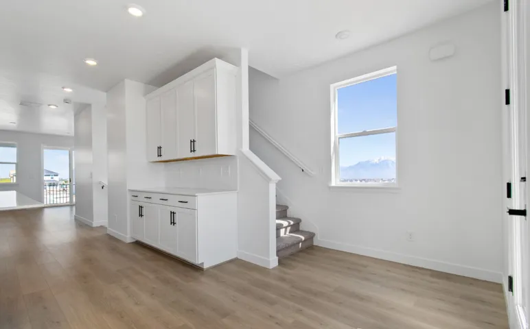 Spacious room featuring wood-finish flooring, white built-in cabinetry with black hardware, recessed lighting, and a window offering a mountain landscape