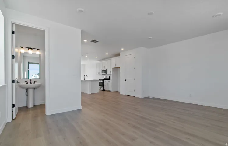 Open-concept main living area with wood-finish flooring, recessed lighting, and white walls
