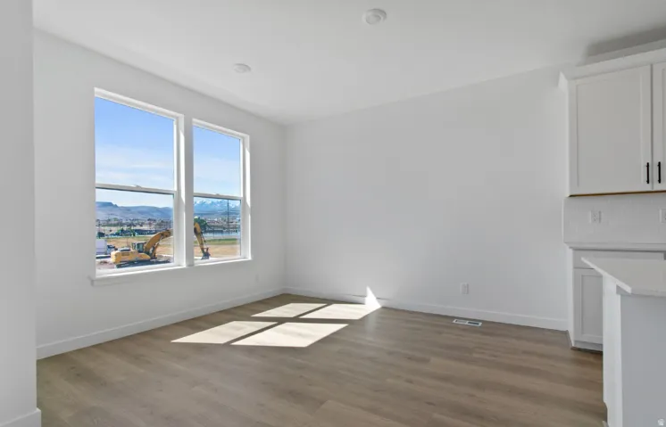 Bright room featuring dual windows, recessed lighting, wood-finish flooring, and white cabinetry