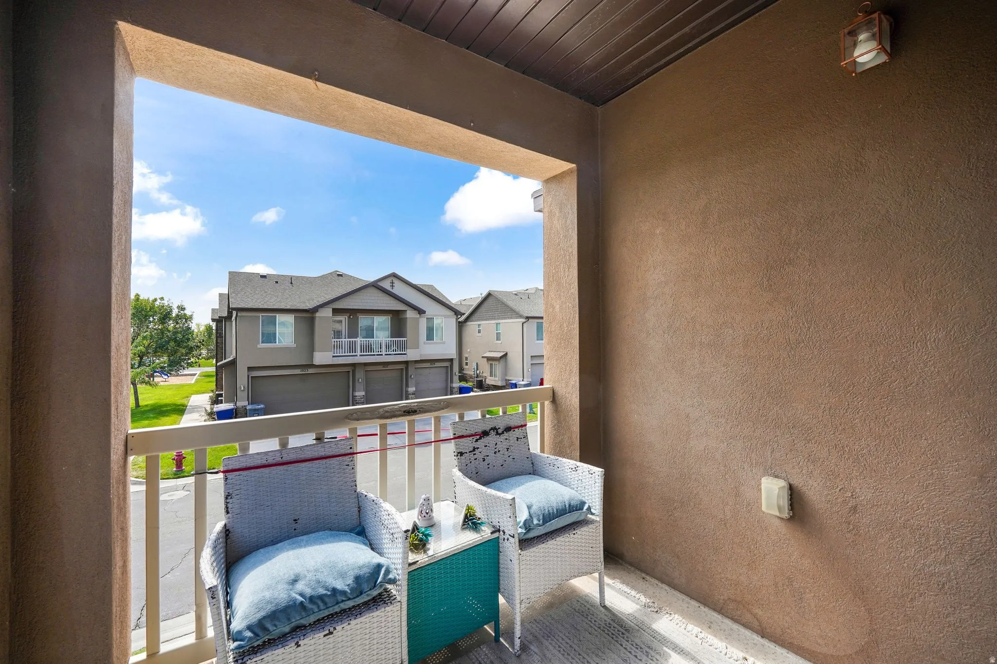 Outdoor balcony featuring a stucco exterior, a wood-paneled ceiling, and a mounted exterior light fixture