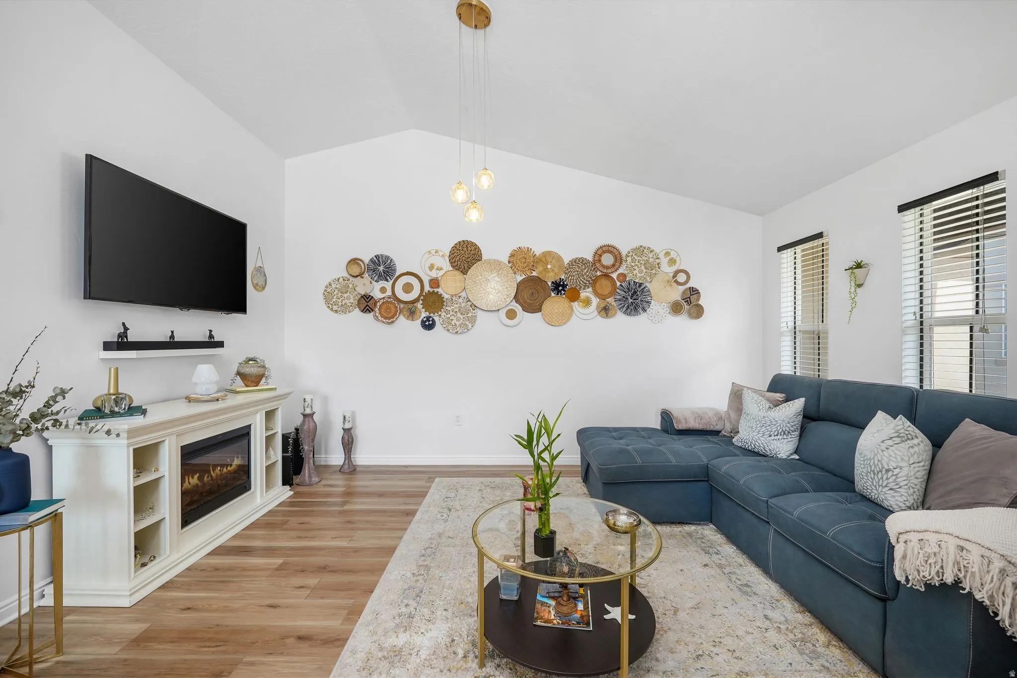 Spacious living area featuring vaulted ceilings, wood-finish flooring, and multiple windows with blinds
