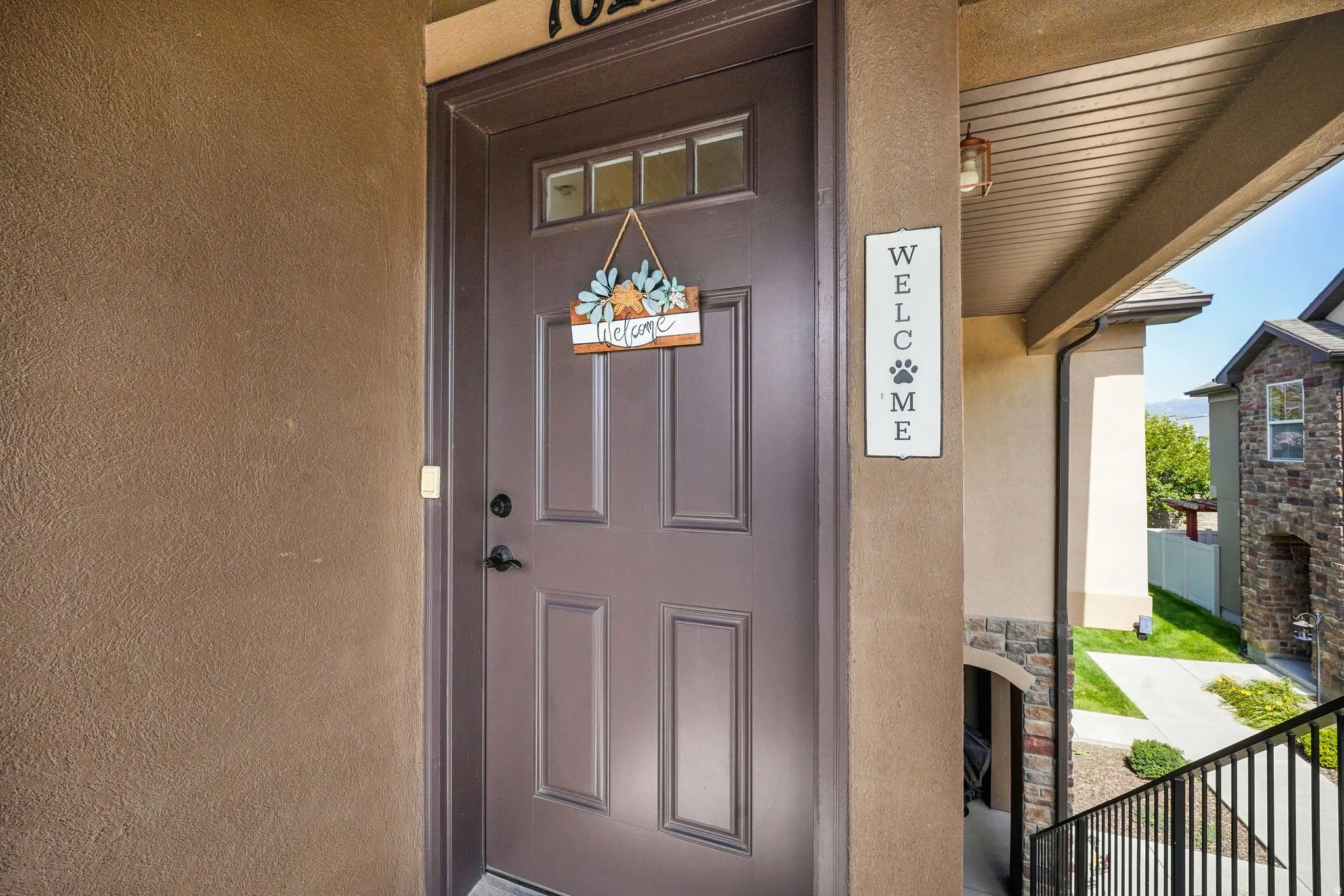 Front entrance featuring a paneled door with transom windows, stucco exterior, and an overhead porch light