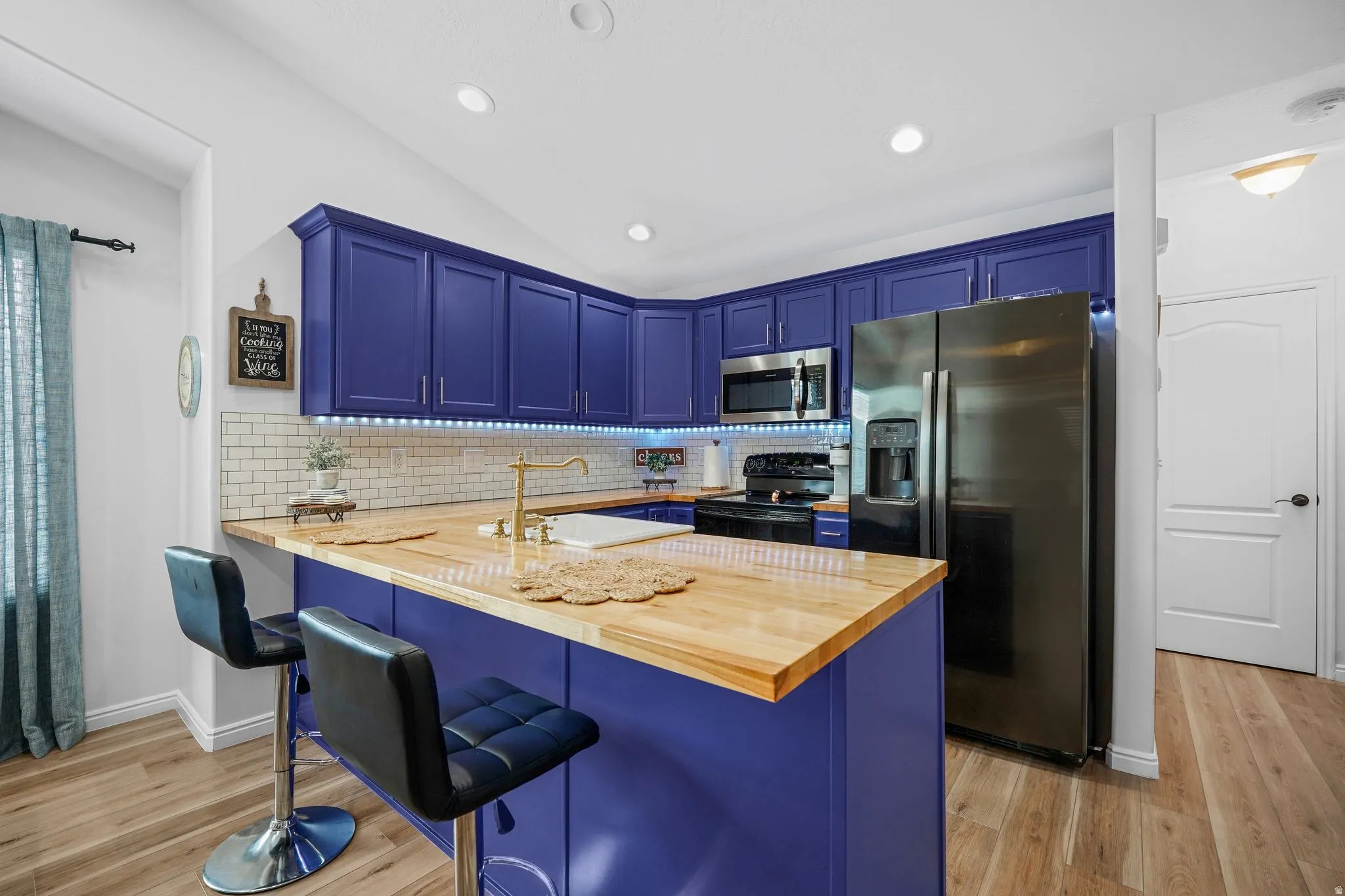 Updated kitchen with butcher block countertops, subway tile backsplash, farmhouse sink, modern lighting