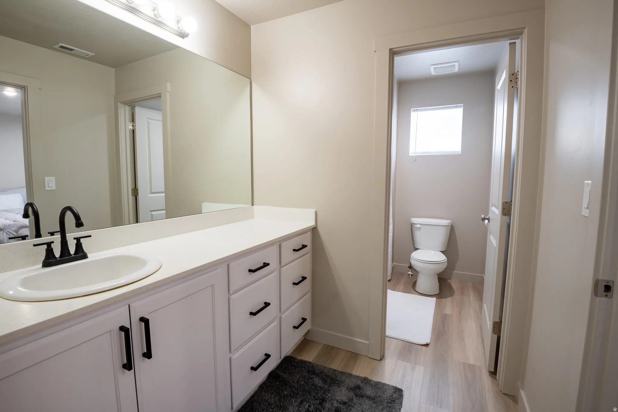 Bathroom featuring a white vanity with integrated sink, black matte faucet, and ample counter space