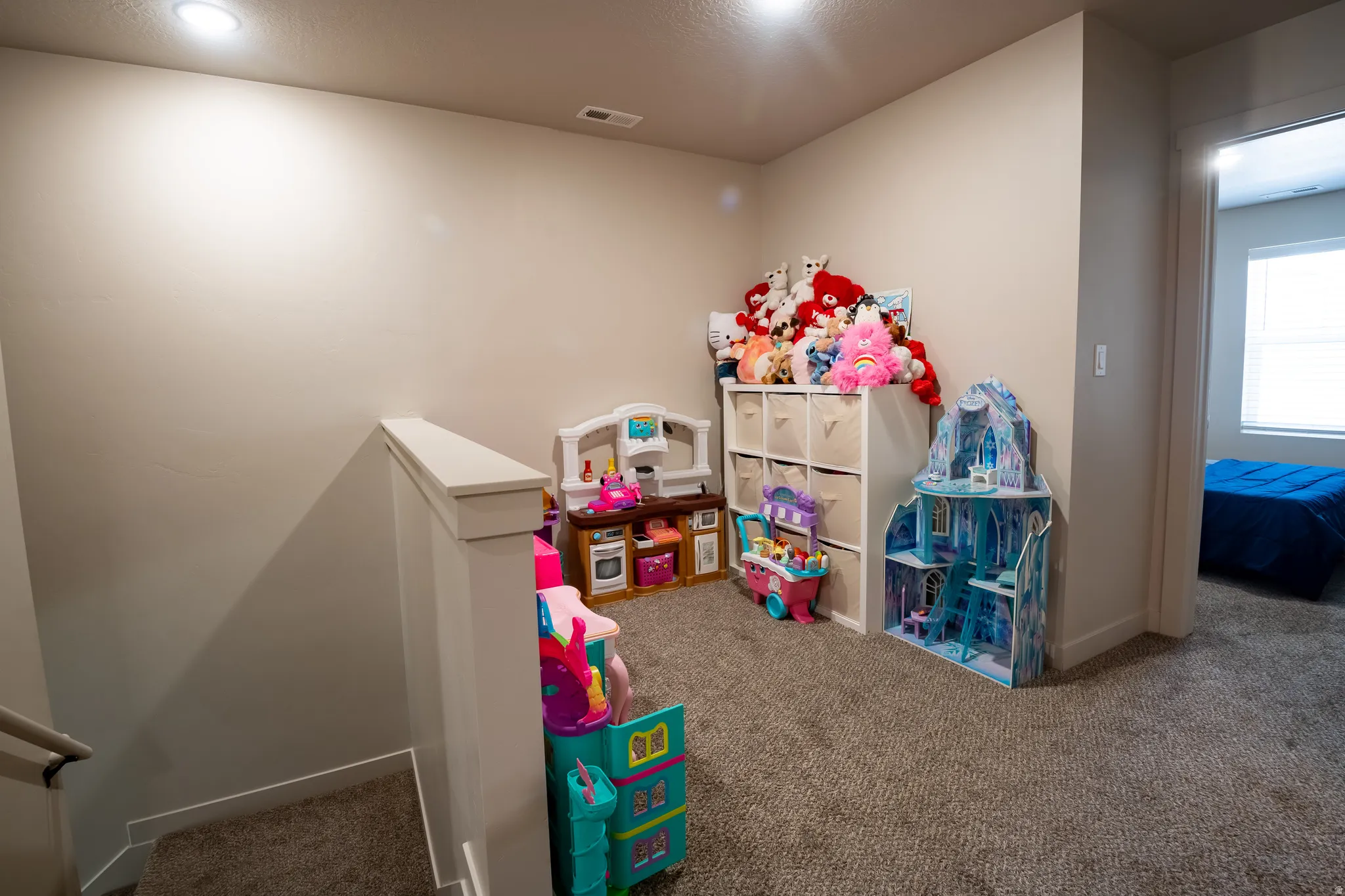 Carpeted landing area featuring a recessed light, neutral wall paint, white trim, and a doorway opening into a room with a window