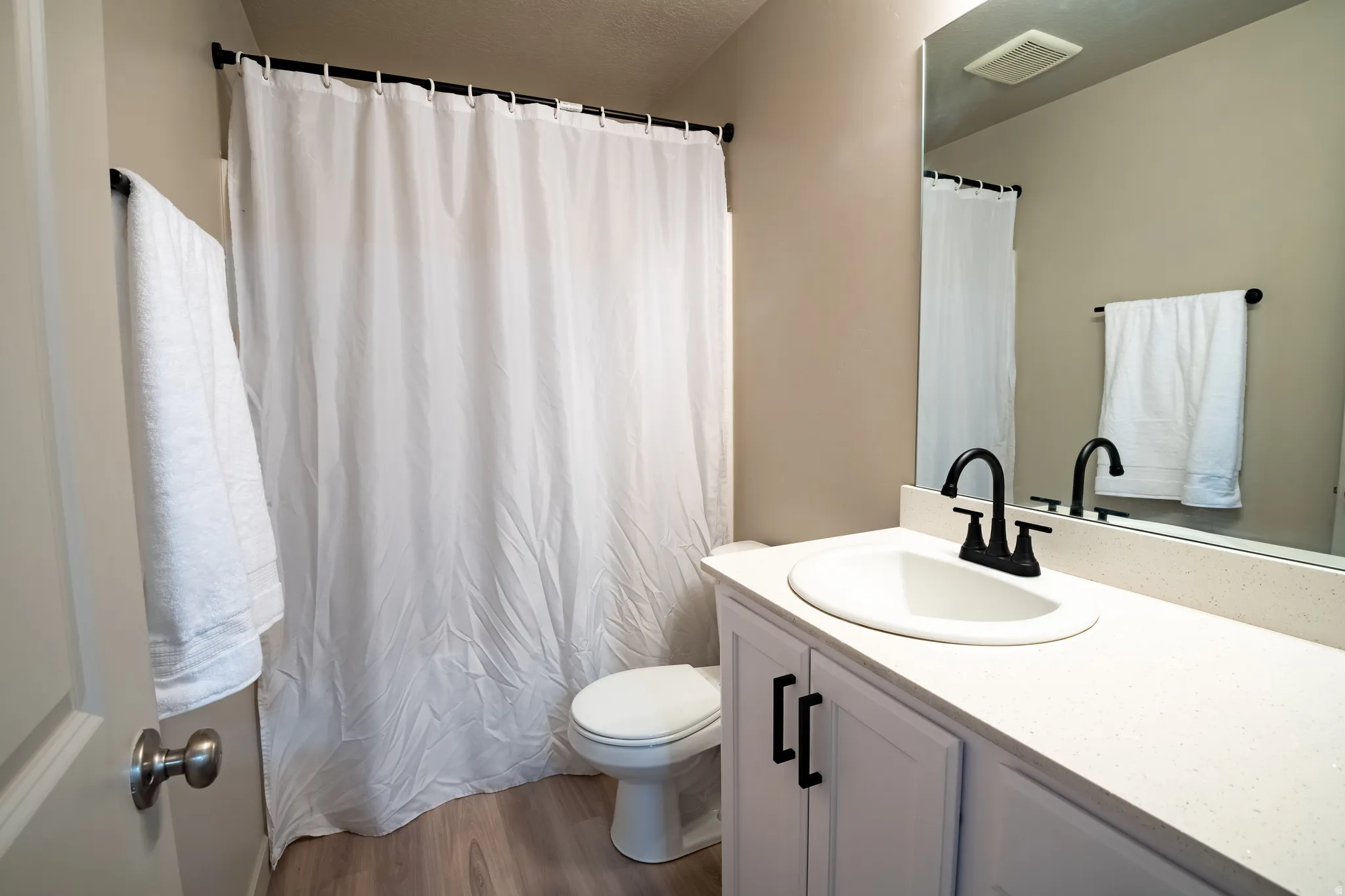 Bathroom featuring a white vanity with black hardware, an integrated sink, and a black faucet