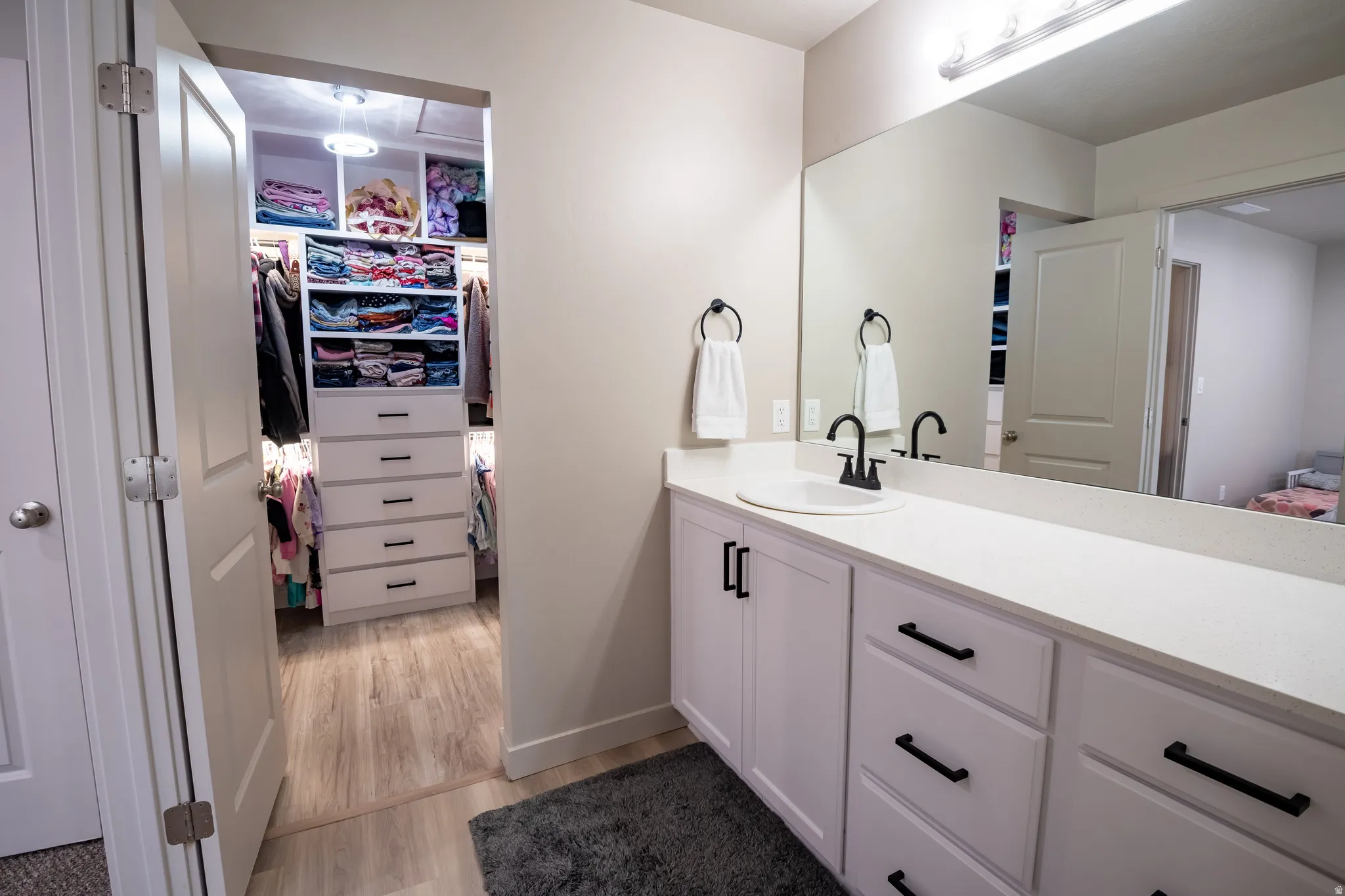 Vanity with a white countertop and integrated sink, matte black faucet, and white cabinetry with black hardware