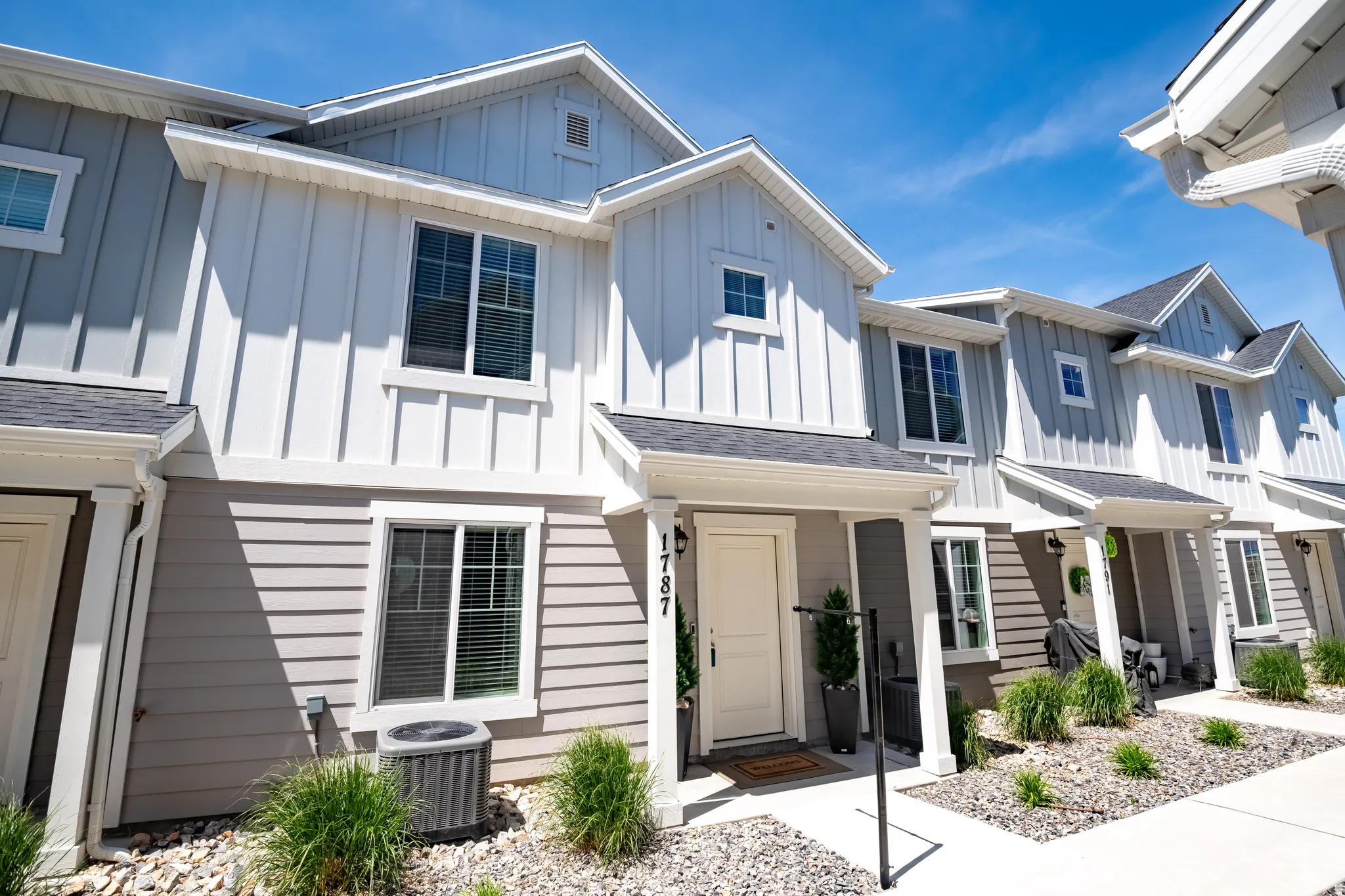 Contemporary townhome exterior featuring a two-tone facade with white board-and-batten and gray horizontal siding