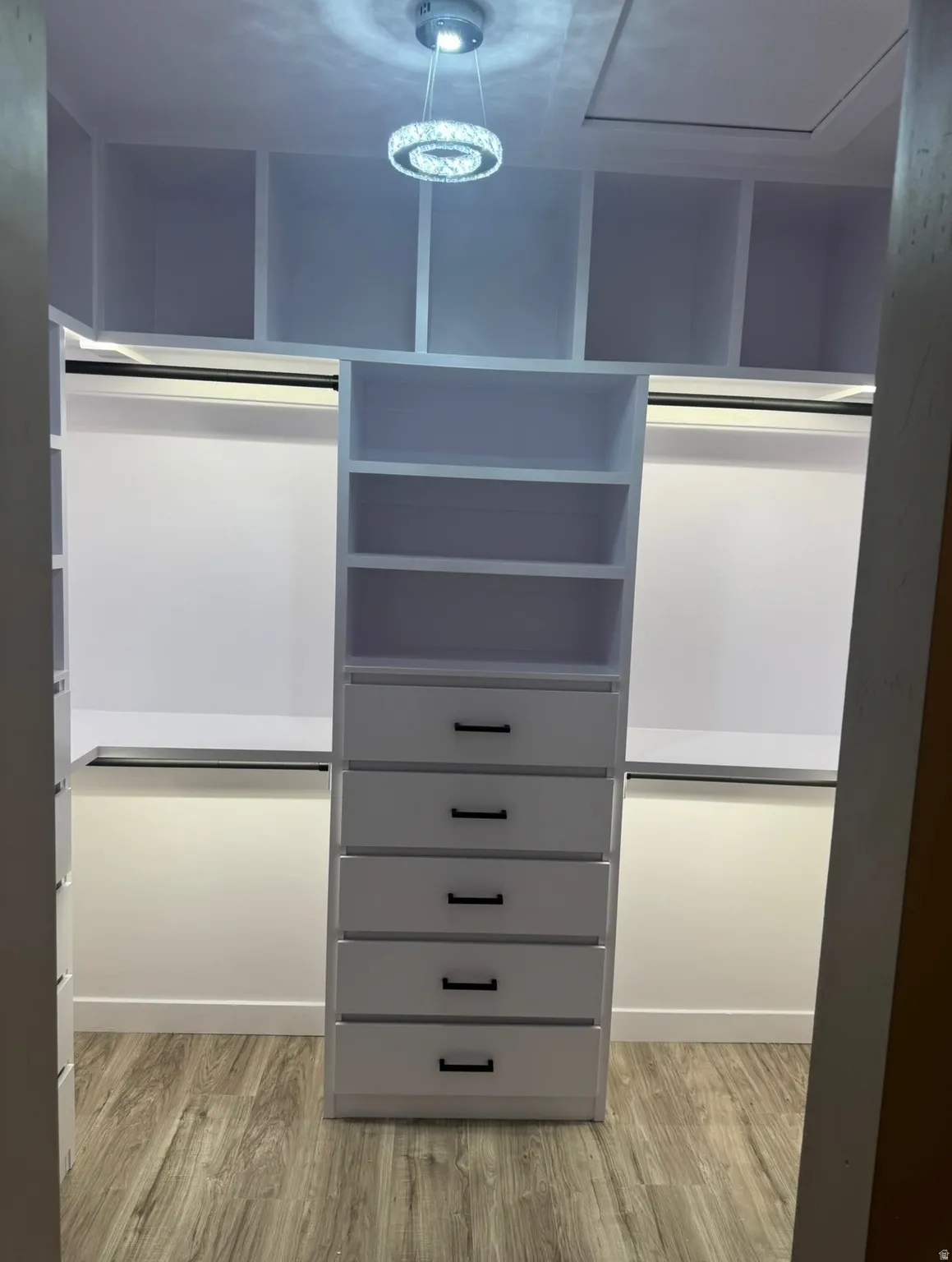 Custom closet system featuring multiple open shelves, built-in drawers with black hardware, and hanging rods