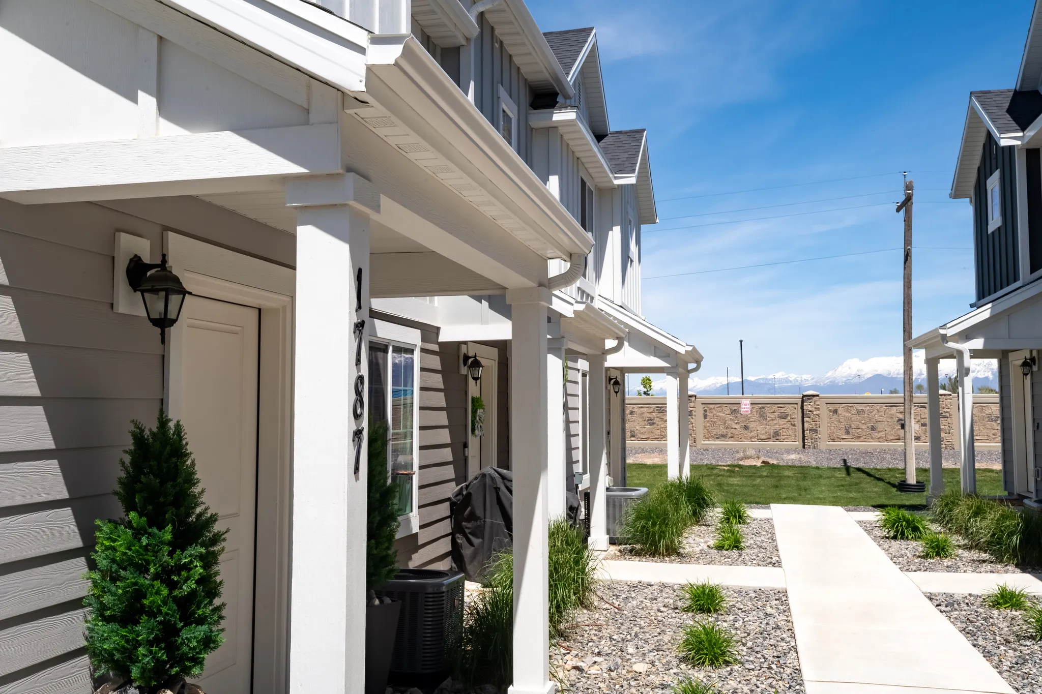 Gray siding exterior with white trim, featuring a covered entryway with a decorative sconce