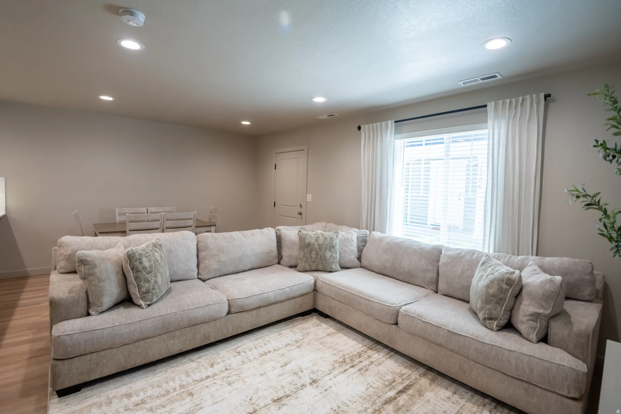 Open-concept living area featuring light-toned walls, recessed lighting, and wood-finish flooring