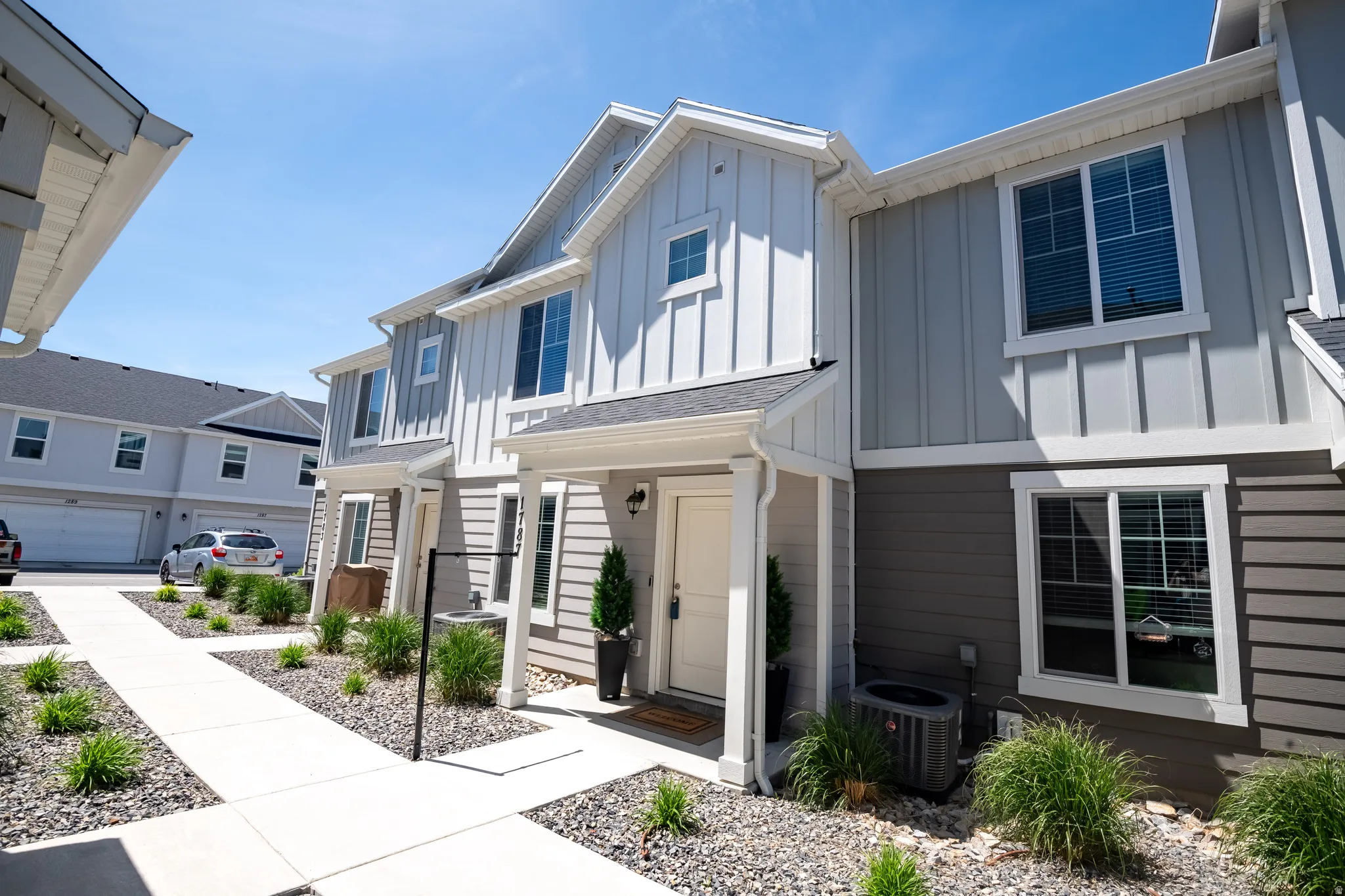 Two-story townhome featuring a covered entry, vertical and horizontal siding, and multiple windows with white trim