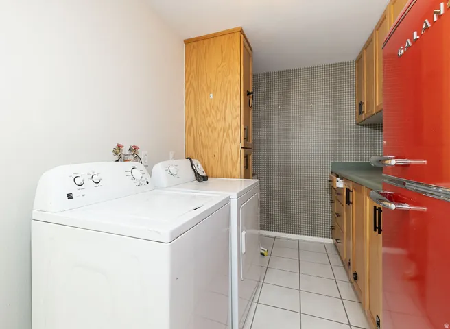 Utility space featuring wood-finish cabinetry, a patterned accent wall, and tiled flooring