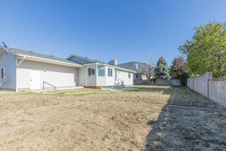 Expansive backyard featuring a block privacy fence, mature trees, and a sunroom with multiple windows