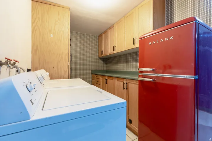 Laundry area featuring wood-finish cabinetry with black hardware, a green countertop, and a checkered wall pattern