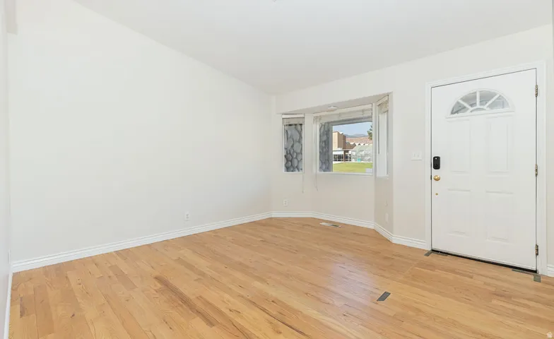 Entryway featuring wood-finish flooring, white baseboards, and a bay window