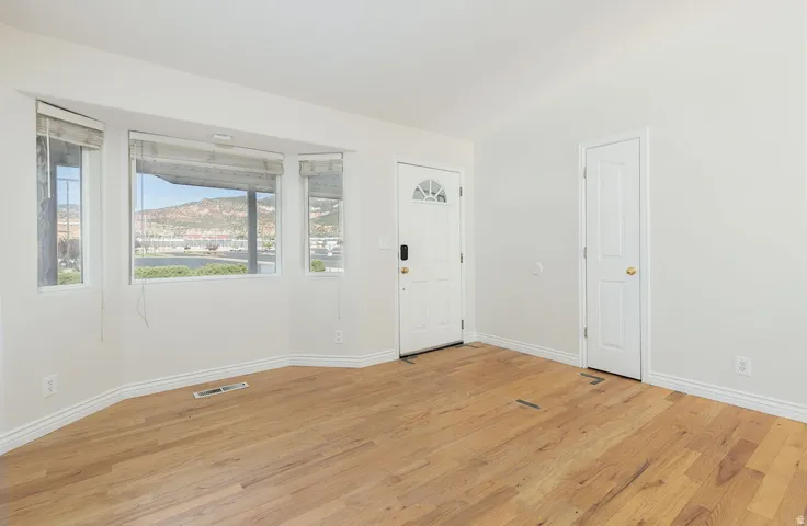 Bright interior space featuring wood-finish flooring, white baseboards, and a bay window