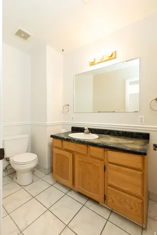 Bathroom vanity with a dark countertop and integrated sink, light wood-finish cabinetry, and a large wall-mounted mirror
