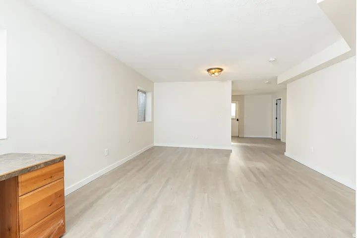 Spacious room featuring light wood-finish flooring, neutral wall tones, and recessed lighting