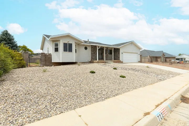 Siding exterior with stone accents, a concrete driveway, and a white garage door
