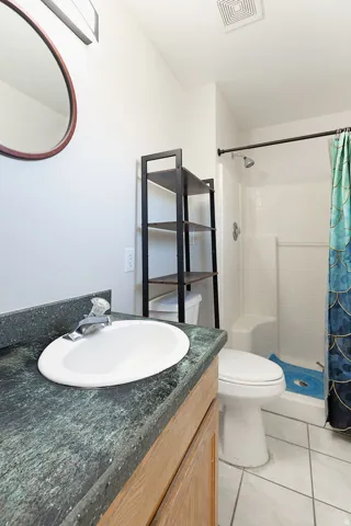 Bathroom featuring a vanity with a dark speckled countertop, an oval sink, and wood cabinetry