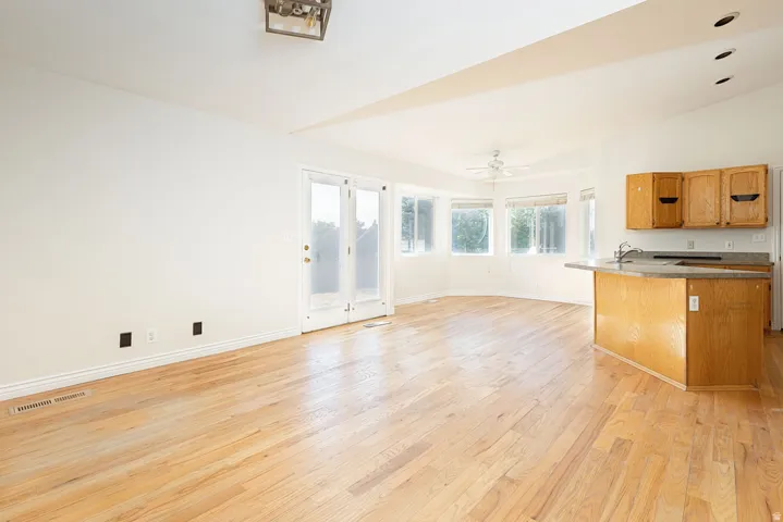 Open-concept living area with wood-finish flooring, a kitchen island with sink, and a bay window