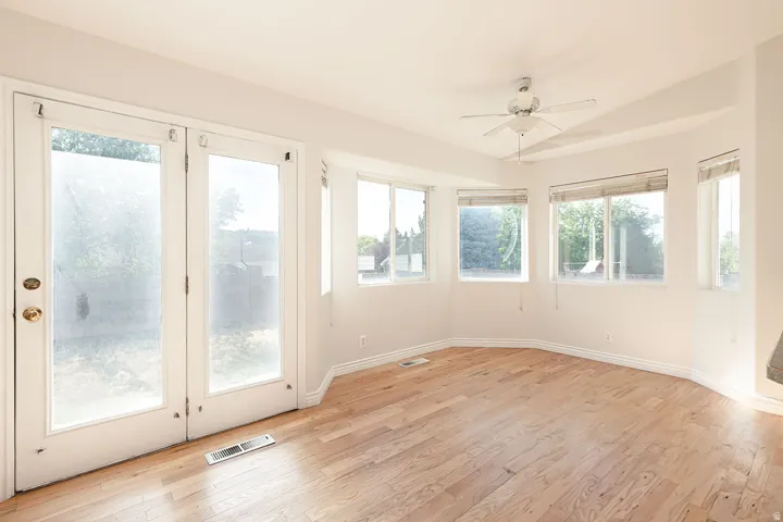 Room featuring wood-finish flooring, white baseboards, and a ceiling fan