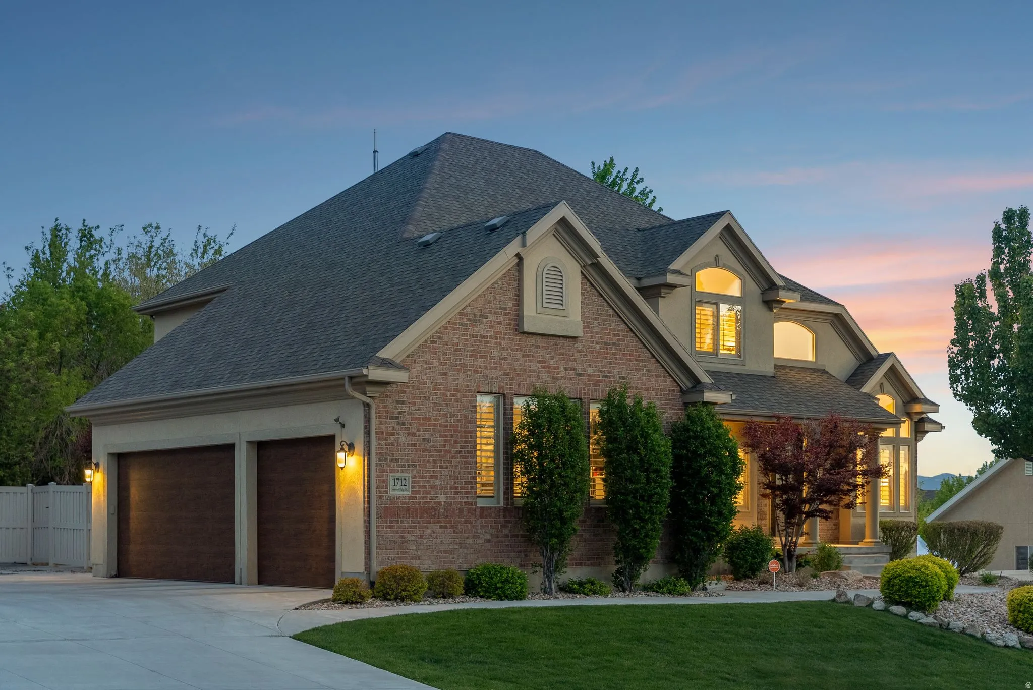 Brick and stucco exterior featuring multiple gables and a dark shingle roof