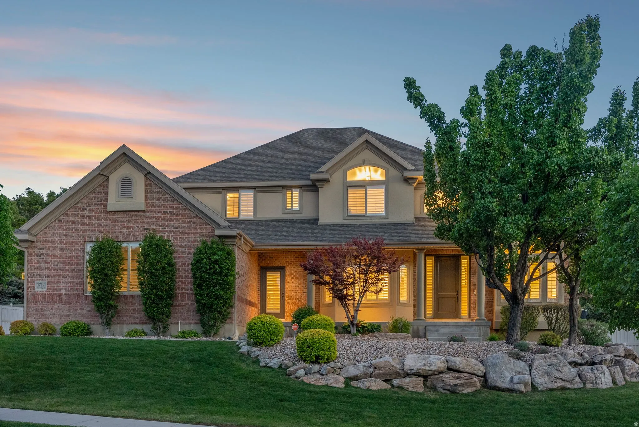 Brick and stucco exterior with a covered front porch featuring stone columns and a transom window