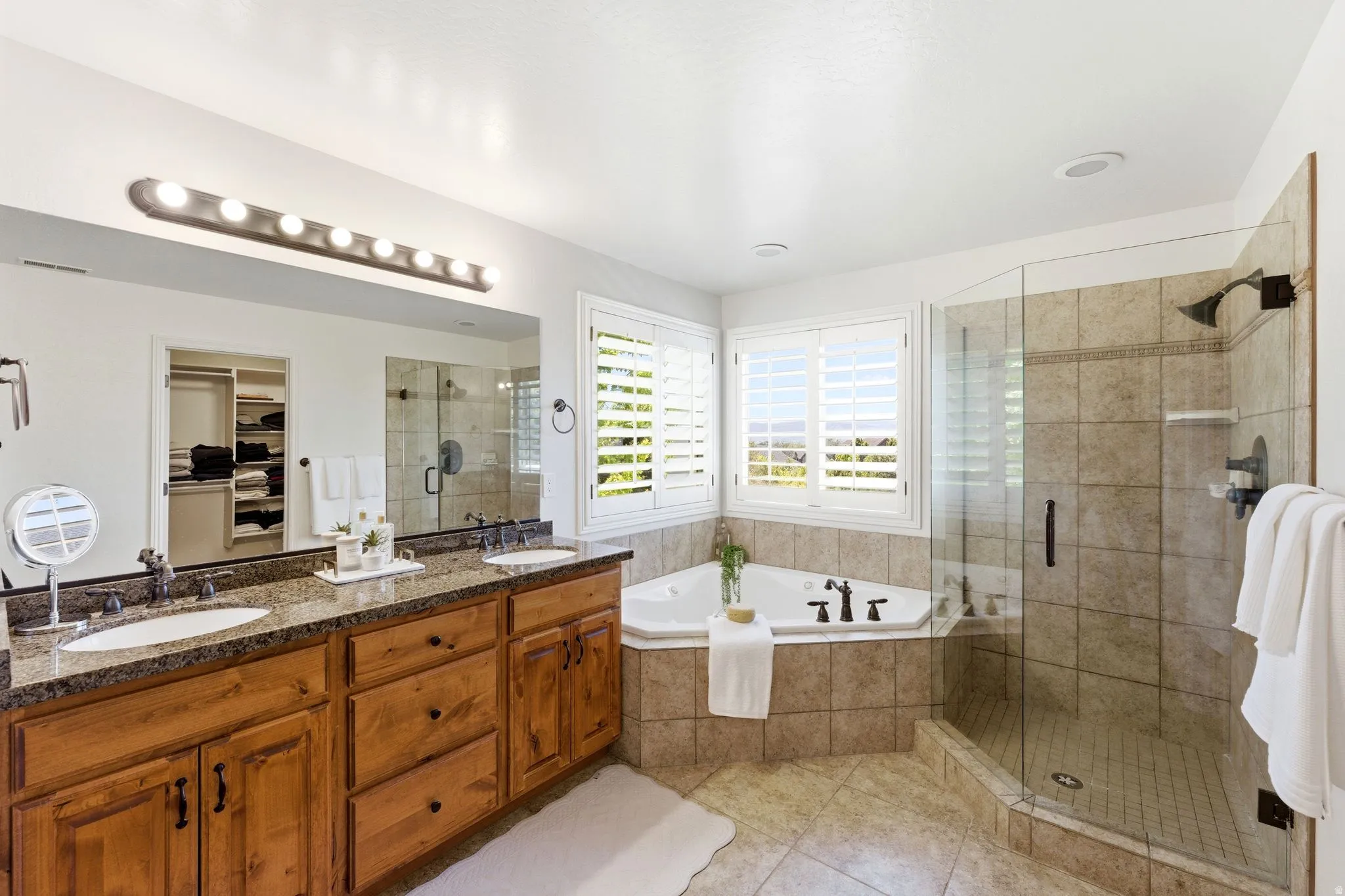 Bathroom featuring a dual vanity with wood cabinetry and a stone countertop